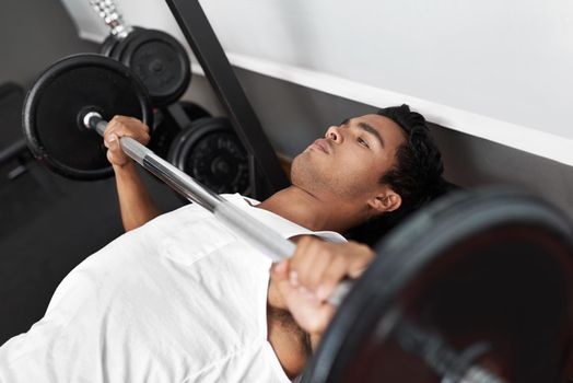 Pump that iron. A young ethnic man exercising in the gym.