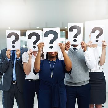 Its a question of success. Shot of a group of businesspeople holding placards with question marks in front of their faces.