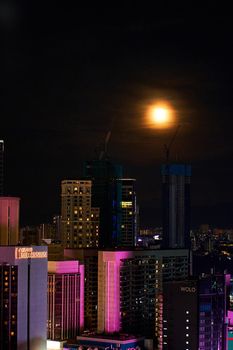 Bright full moon in the night sky over the metropolis
