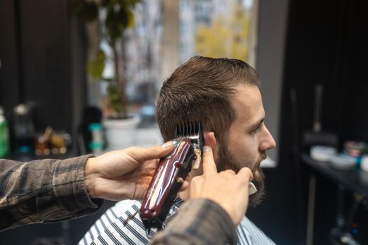 Master in barbershop makes men's haircutting with hair clipper