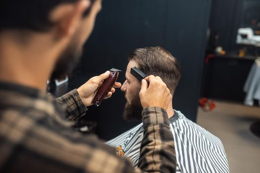 Master in barbershop makes men's haircutting with hair clipper