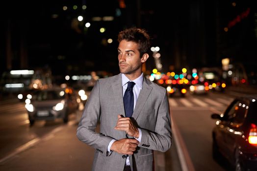 Suave in the city. A handsome businessman posing in the middle of a busy city street at night.