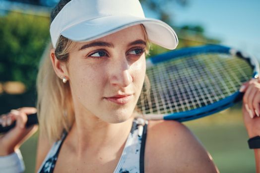 Nobody who ever gave it their best regretted it. Shot of a sporty young woman standing on a tennis court with a tennis racket.