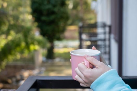 Woman drinking hot drink standing on the balcony.