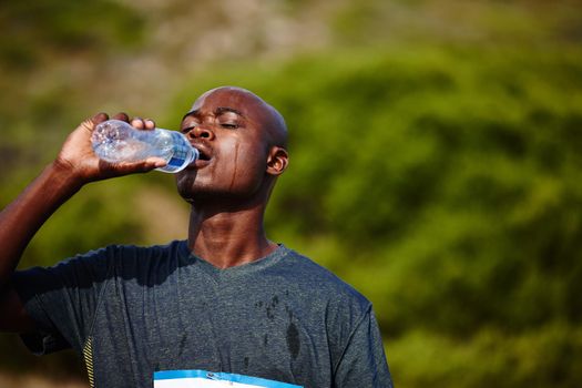 H2O - A runners best friend. Shot of a young male runner drinking from his water bottle during a race.