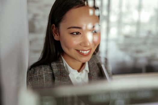 Portrait of smiling asian business woman standing behind glass in office