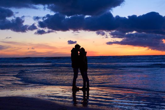Nature setting the scene for romance. Silouehette of a couple kissing on the beach at sunset.
