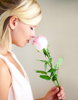 Rose for a rose. Profile of a young woman smelling a pink rose.