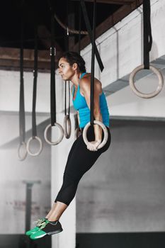 On the rings. Full length shot of a young woman working out on the gymnastics rings.