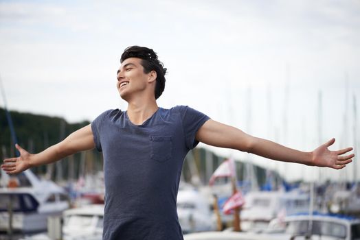 Feeling free and alive. A young man with arms outstretched relishing the breeze.