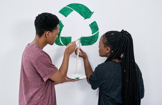 Dont throw your tomorrow awayrecycle. Shot of a young couple painting a recycle symbol on a wall.