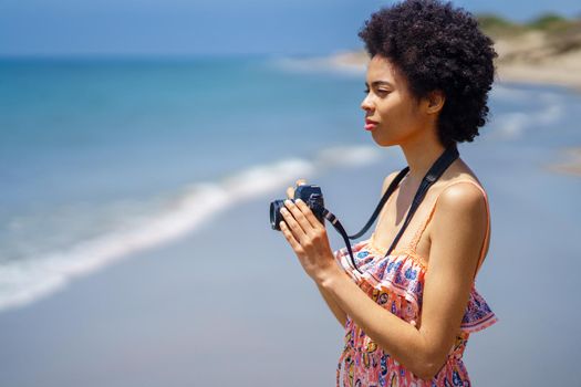 Black woman with camera on beach