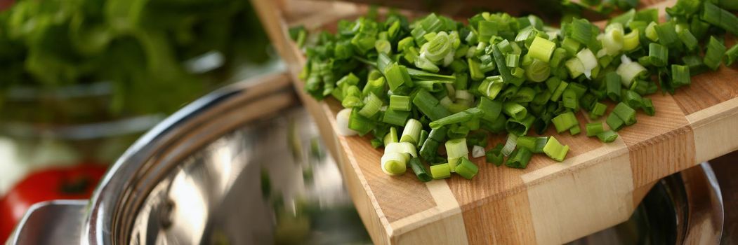 Put chopped green onions in a steel pan, close-up
