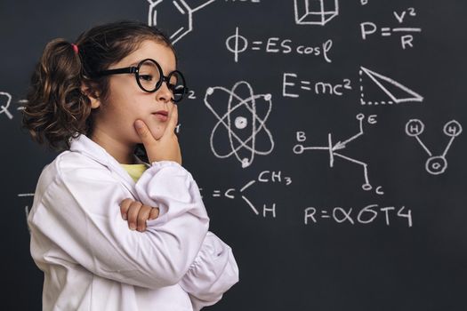 pensive little girl scientist in lab coat