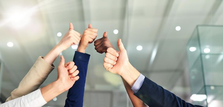 Thumbs up to success. Shot of a group of hands showing thumbs up in an office.