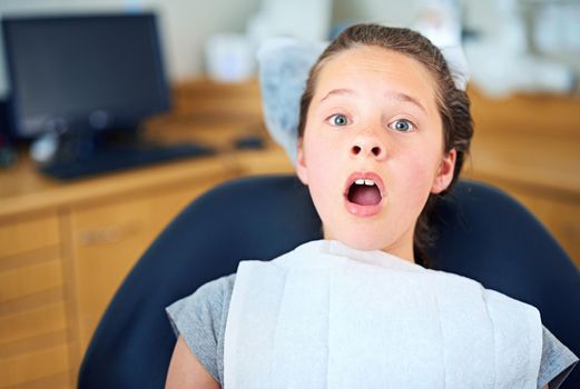 In the hot seat. Shot of a young girl looking terrified while sitting in a dentists chair.