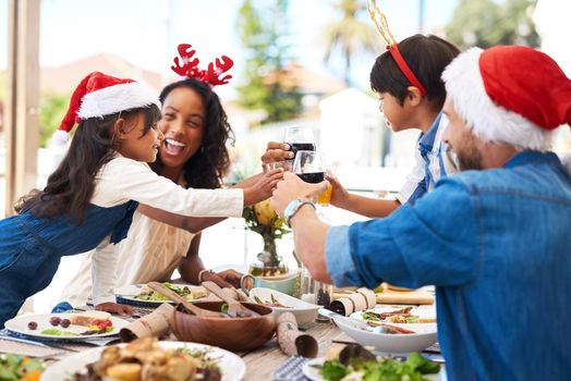 Were all feeling the holiday spirit today. Shot of a beautiful young family sharing a toast while enjoying Christmas lunch together outdoors.