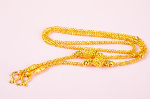 Gold necklace on pink background.