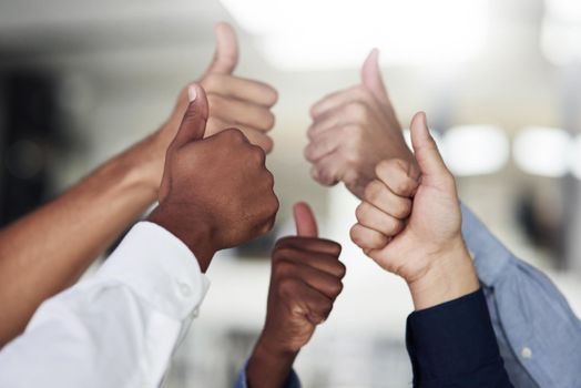 We say yes to success. Shot of a group of unidentifiable businesspeople showing thumbs up in the office.