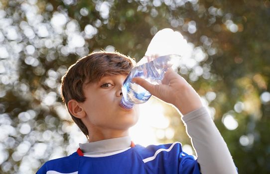 Boys will be boys. Shot of a young boy in sports clothing drinking from a water bottle.