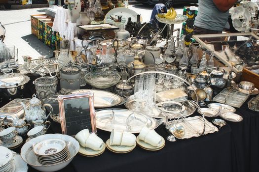 Assorted silverware, glassware and crockery dishes on a table at a flea market