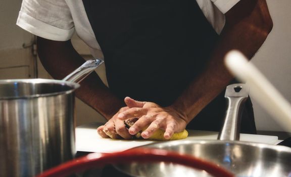 Close-up of chef's hands kneading dough on a kitchen worktop
