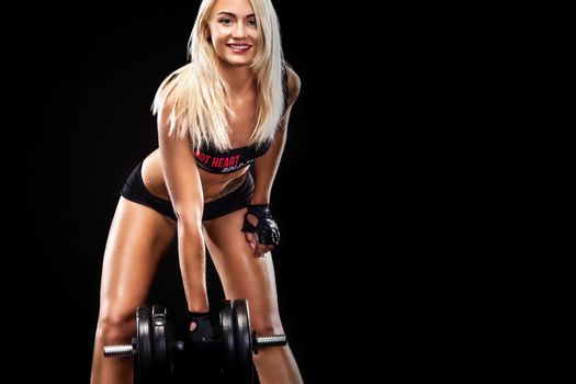 Sporty and fit beautiful woman with dumbbell exercising at black background to stay fit. Fitnwss workout motivation.