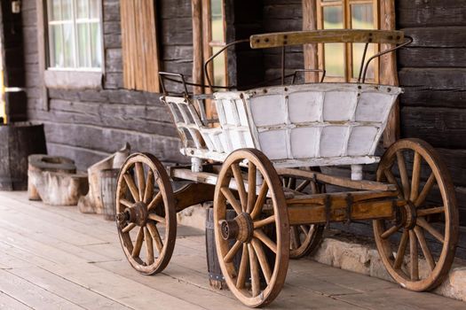 An empty antique carriage stands on a ranch in the wild West
