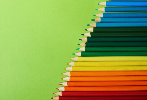 All the colours of the rainbow. Studio shot of different coloured pencils against a green background.