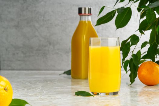 Glass of orange juice and orange juice bottle. Fresh tropical juice.
