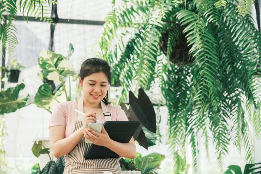 Young woman plant shop owner is checking customer order from website