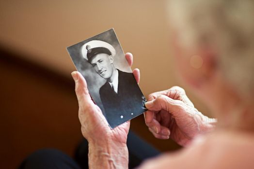He lived a life of honor. Cropped shot an elderly woman holding an old black and white photograph of a man.