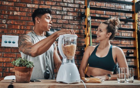 I saw this particular recipe on a dieting blog. Cropped shot of two young sportspeople making fruit milkshake while working in a gym.