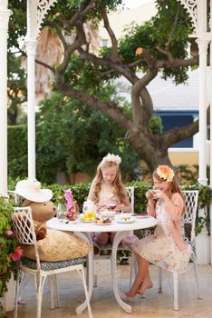 Fancy a cuppa. Two young girls having a tea party in the backyard.