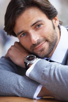 Hes a well groomed man. A cropped portrait of a handsome businessman leaning on a table.