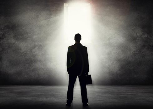 The corporate world beckons. Conceptual shot of a businessman looking towards a bright doorway.