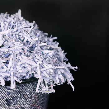 Leaving no paper trail. Studio shot of shredded paper in a dustbin against a black background.