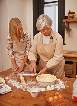 Learning grandmas secret recipes. Shot of a grandmother teaching her granddaughter how to bake.
