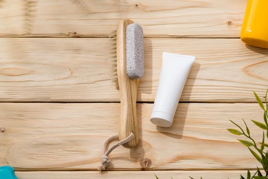 Foot brush and foot cream on wooden background