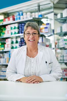 Speak to me for all of your health related queries. Portrait of a happy mature woman working in a pharmacy.