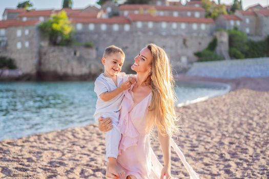 Mother and son tourists on background of beautiful view St. Stephen island, Sveti Stefan on the Budva Riviera, Budva, Montenegro. Travel to Montenegro concept