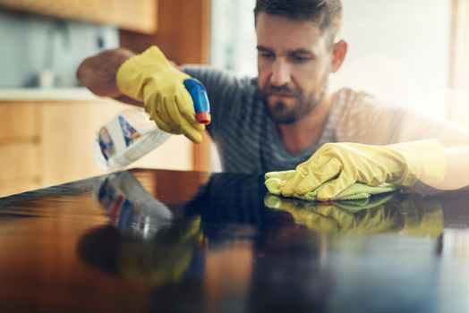 Germs, aint nobody got time for that. Shot of a young man cleaning the kitchen counter at home.