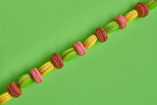 Colored macaron or macaroon, sweet meringue-based confection on green background. Close-up, copy space.