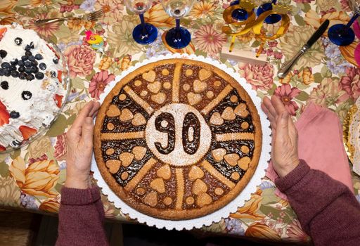 Senior woman holds her 90's birthday cake