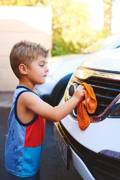 Daddy will be proud. Cropped shot of an adorable little boy washing a car outside.