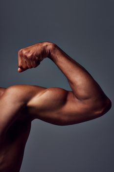 What do you think about this. Studio shot of an unrecognizable muscular sportsman flexing his bicep against a grey background.