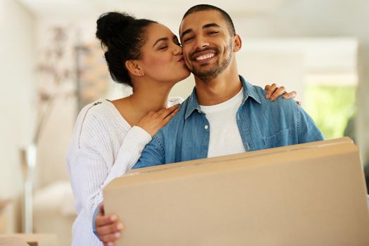 Taking their relationship to a whole new level. Portrait of a happy young couple carrying cardboard boxes into their new home.