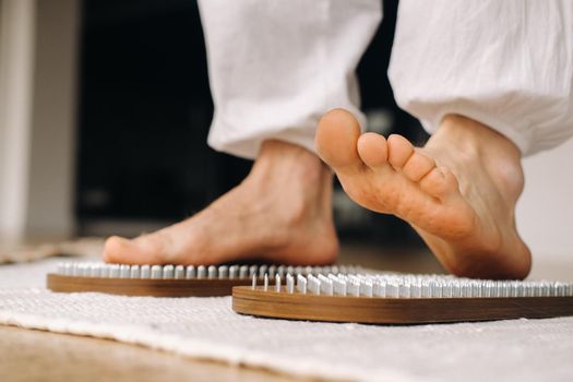 The man's feet are next to boards with nails. Yoga classes