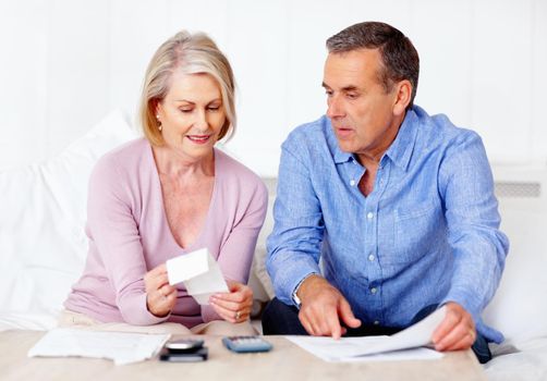 Mature man and wife calculating expenses using calculator. Portrait of a mature man and wife calculating monthly expenses using calculator.