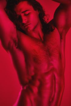 Breathtaking muscles. Studio shot of a muscular young man posing shirtless against a red background.